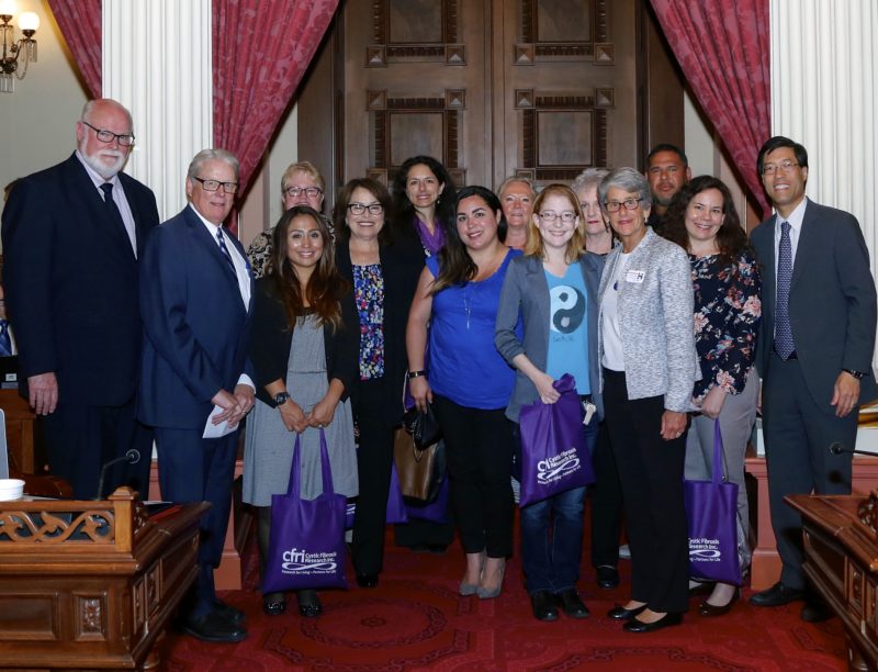 Advocates stand together on the floor of the California Senate, alongside legislators.